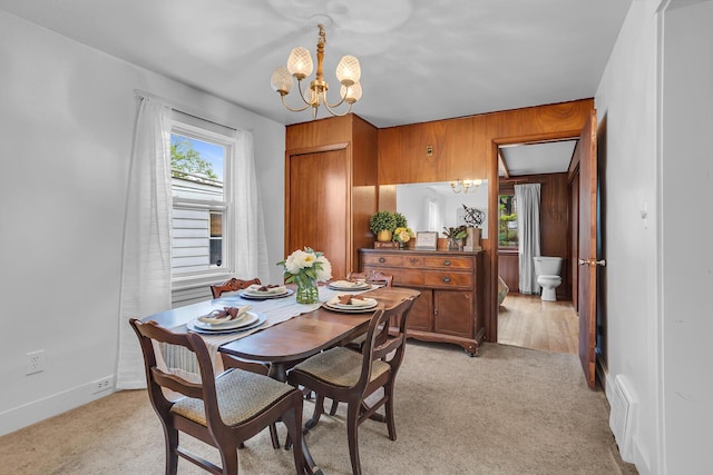 1319 Rhodes St, Jackson, MI 49202 - dining space featuring a chandelier, light colored carpet, baseboards, and wood walls