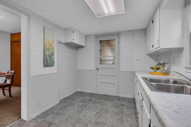 1319 Rhodes St, Jackson, MI 49202 - kitchen featuring a sink, light countertops, white cabinets, a paneled ceiling, and baseboards