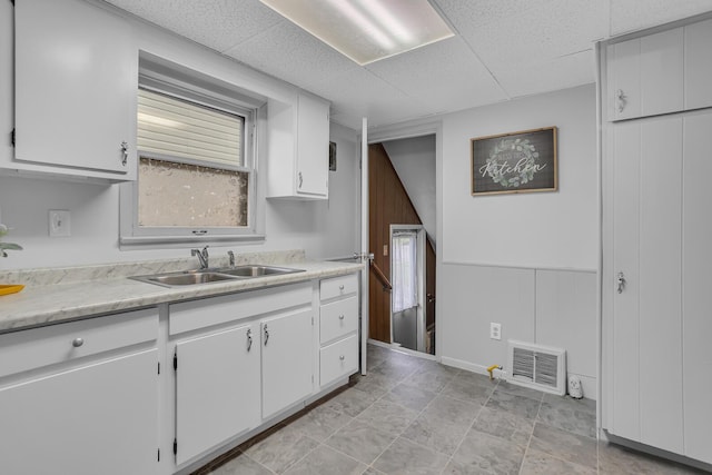 1319 Rhodes St, Jackson, MI 49202 - kitchen with a sink, light countertops, white cabinetry, and a paneled ceiling