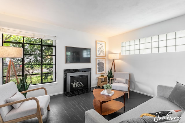 living room with a fireplace with flush hearth, baseboards, and dark wood-style flooring