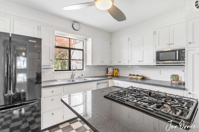 kitchen with ceiling fan, appliances with stainless steel finishes, a sink, white cabinetry, and tasteful backsplash