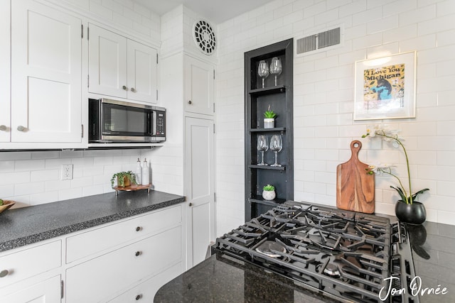 kitchen with backsplash, visible vents, open shelves, white cabinets, and stainless steel microwave