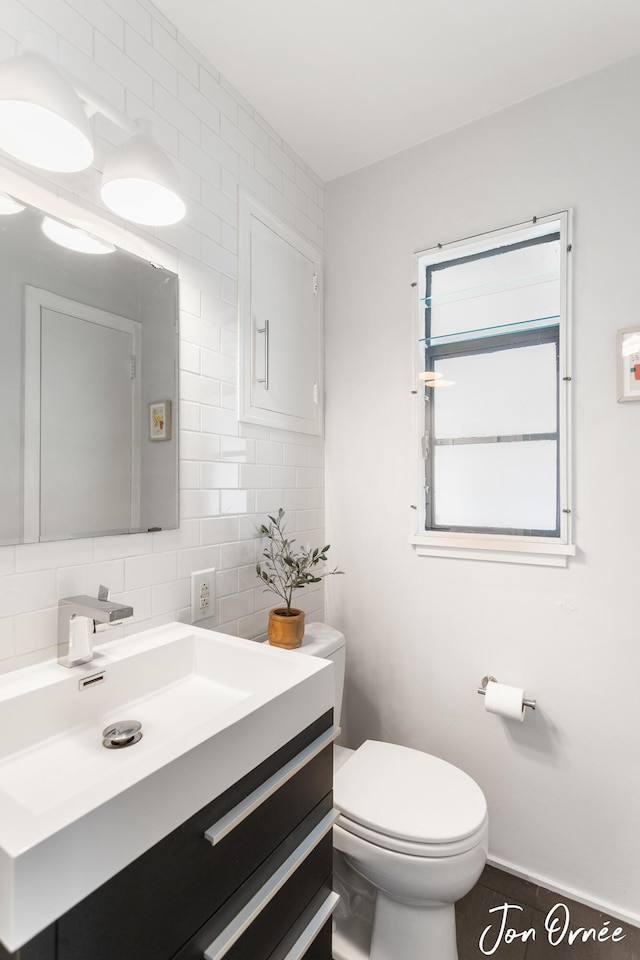 half bathroom featuring vanity, baseboards, backsplash, and toilet