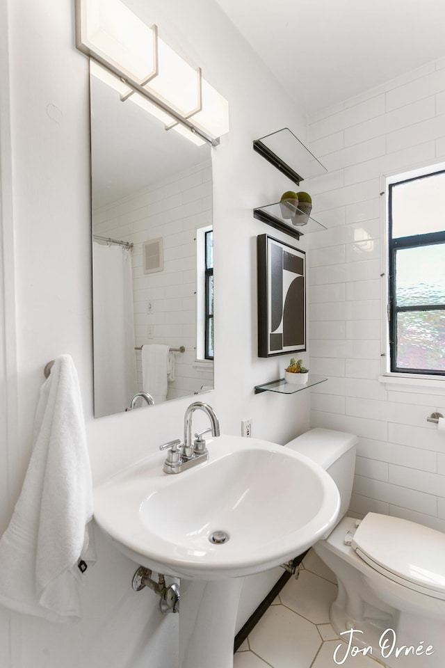 full bathroom featuring tile patterned floors, toilet, and tile walls