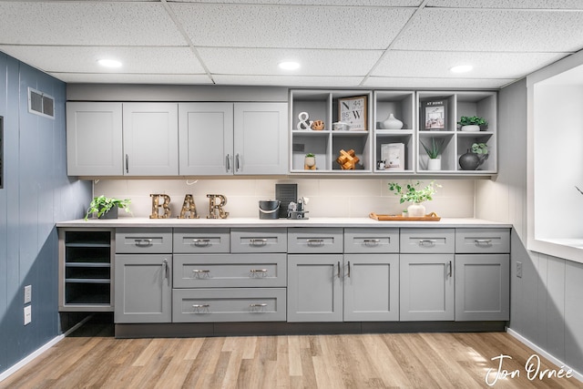 bar with visible vents, a paneled ceiling, and light wood finished floors