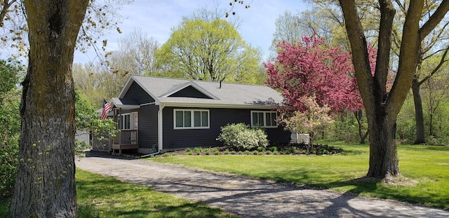 view of front of property featuring a shingled roof and a front lawn