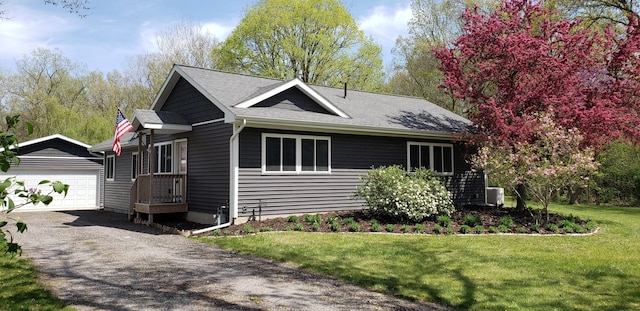 view of front of property with an outdoor structure, central AC, a front yard, roof with shingles, and a detached garage
