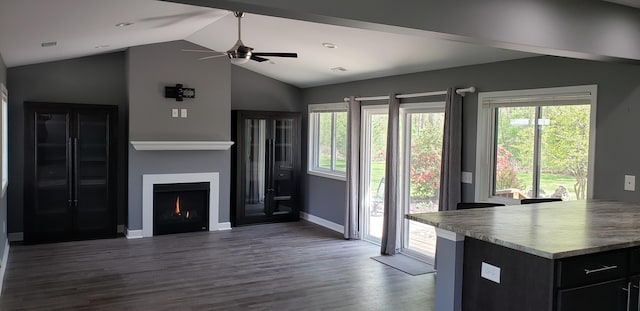 unfurnished living room with plenty of natural light, a ceiling fan, dark wood-style flooring, and lofted ceiling