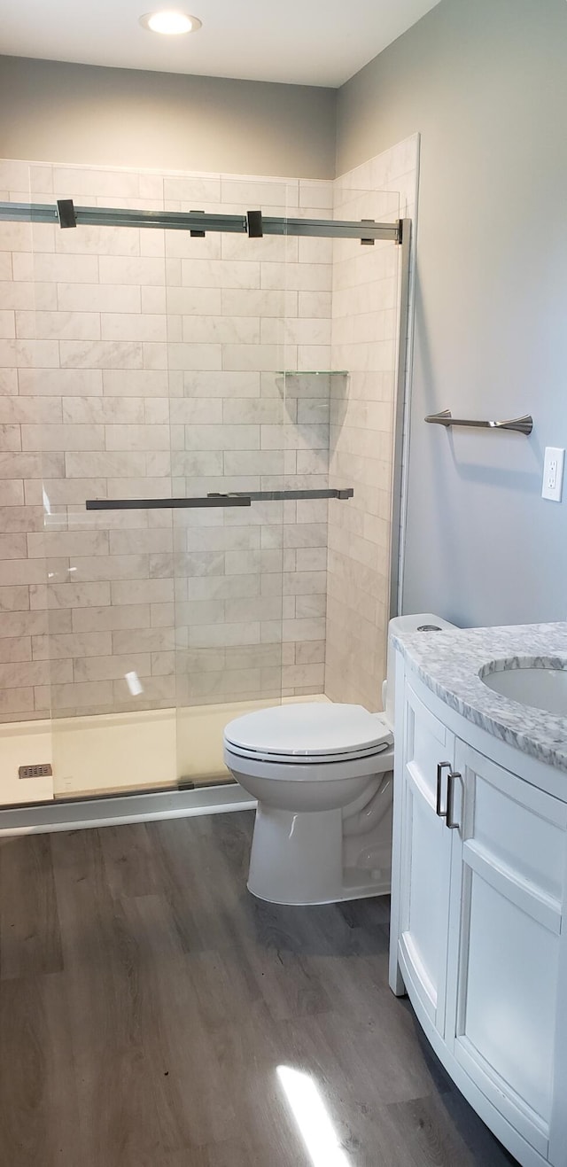 bathroom featuring toilet, recessed lighting, a shower stall, and wood finished floors