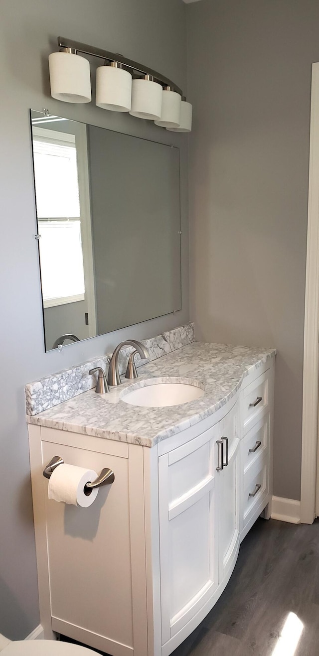 bathroom featuring vanity, baseboards, and wood finished floors