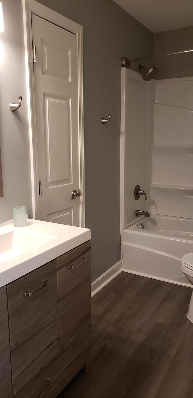 full bathroom with shower / bathing tub combination, wood finished floors, vanity, baseboards, and toilet
