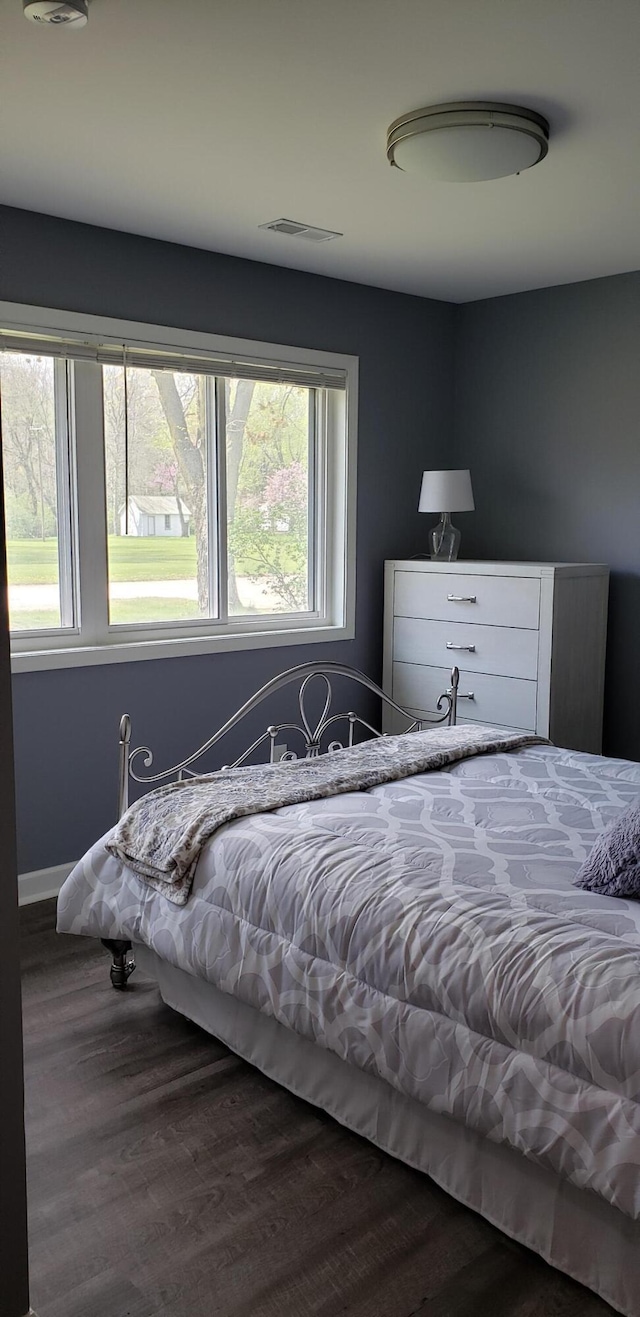 bedroom with dark wood-style floors, multiple windows, and visible vents
