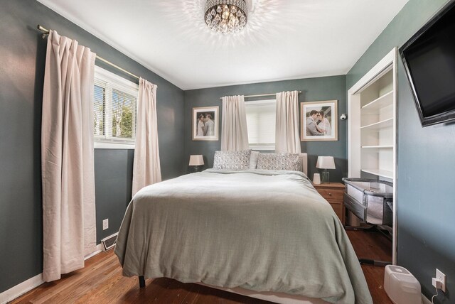 bedroom with an inviting chandelier, baseboards, and wood finished floors