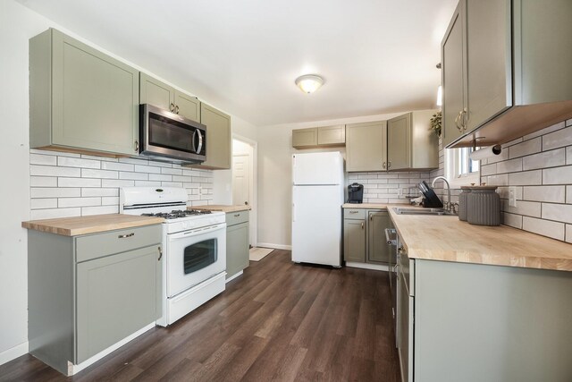 kitchen with dark wood-style flooring, butcher block counters, white appliances, tasteful backsplash, and a sink
