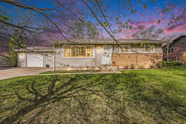 ranch-style home featuring an attached garage, a lawn, and driveway