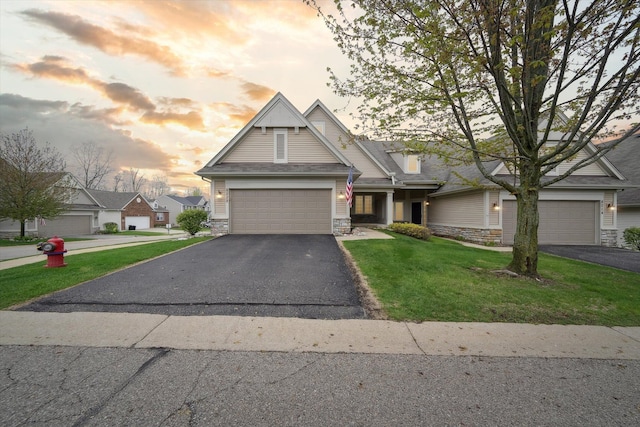 view of front of home with stone siding, asphalt driveway, a garage, and a lawn