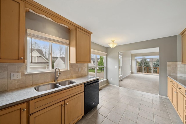 kitchen featuring dishwasher, a sink, baseboards, backsplash, and light stone counters
