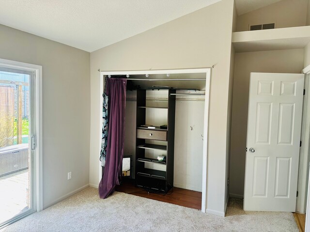 unfurnished bedroom featuring visible vents, vaulted ceiling, baseboards, a closet, and carpet