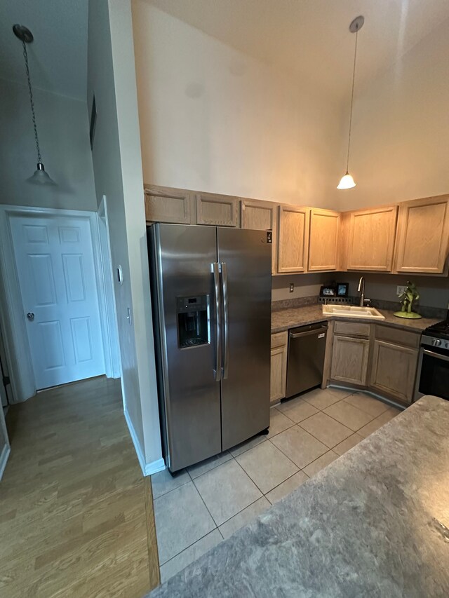 kitchen with decorative light fixtures, appliances with stainless steel finishes, light tile patterned floors, high vaulted ceiling, and a sink