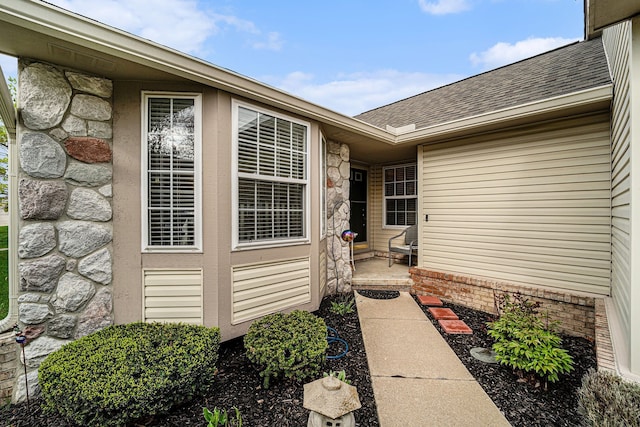 property entrance featuring stone siding and a shingled roof