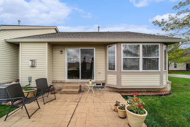 rear view of property with a yard, a shingled roof, central AC unit, a patio area, and entry steps
