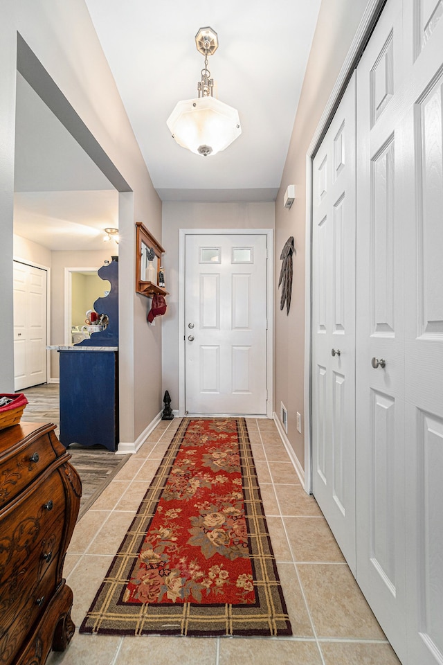 doorway with baseboards and light tile patterned floors