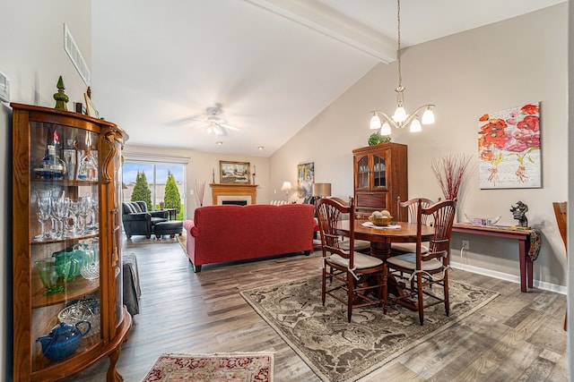 dining space featuring visible vents, wood finished floors, ceiling fan with notable chandelier, and vaulted ceiling with beams
