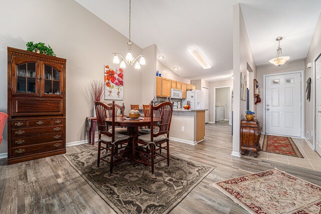dining space with vaulted ceiling, baseboards, and light wood-style floors