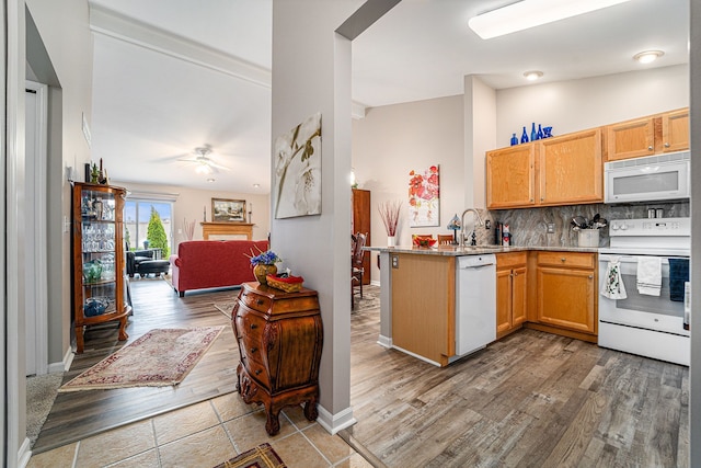 kitchen with white appliances, a sink, open floor plan, a peninsula, and decorative backsplash