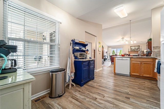 kitchen with light wood finished floors, a peninsula, a notable chandelier, visible vents, and dishwasher