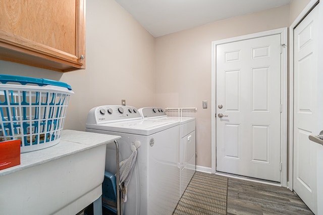 laundry area featuring washing machine and clothes dryer, cabinet space, and dark wood-type flooring