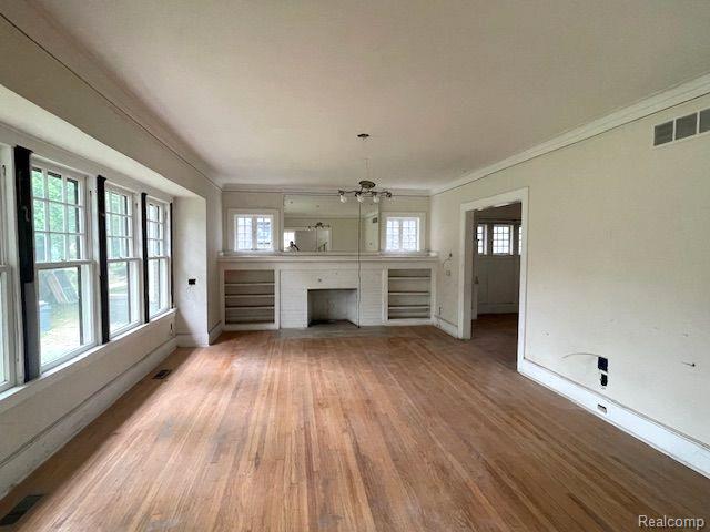 1485 Longfellow St, Detroit, MI 48206 - unfurnished living room with baseboards, a chandelier, light wood-style floors, and ornamental molding