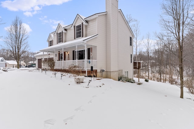 view of snowy exterior featuring a porch and a chimney