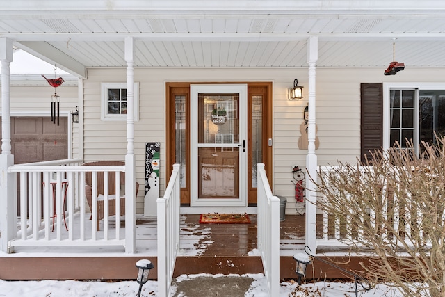 snow covered property entrance with covered porch