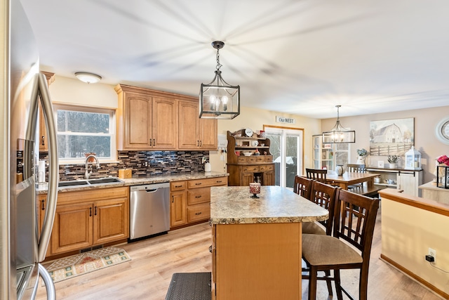 kitchen featuring backsplash, a kitchen island, appliances with stainless steel finishes, a sink, and a notable chandelier