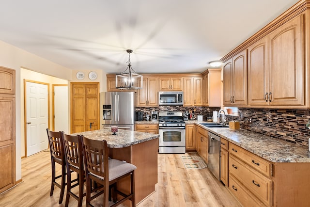 kitchen with appliances with stainless steel finishes, tasteful backsplash, a sink, a breakfast bar, and light wood-style flooring
