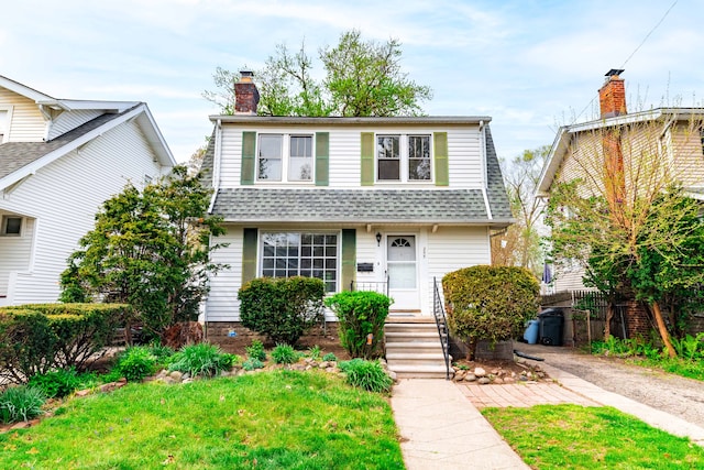 view of front of house featuring a shingled roof, fence, a front yard, and a chimney