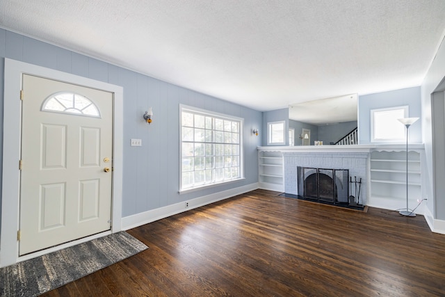entryway featuring baseboards, a brick fireplace, and dark wood-type flooring