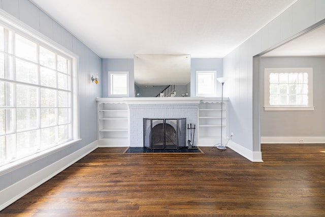 unfurnished living room with baseboards, a fireplace, and dark wood-style floors