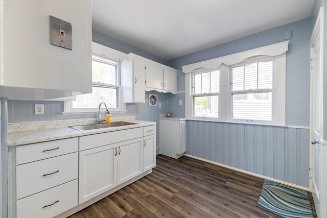 kitchen with wainscoting, baseboards, dark wood-style floors, white cabinetry, and a sink