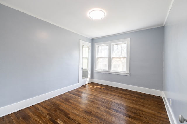 unfurnished room featuring crown molding, baseboards, and dark wood finished floors