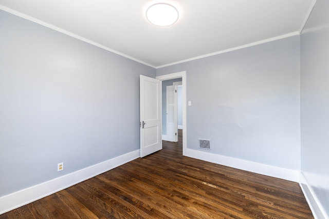 spare room featuring dark wood-style floors, baseboards, visible vents, and ornamental molding