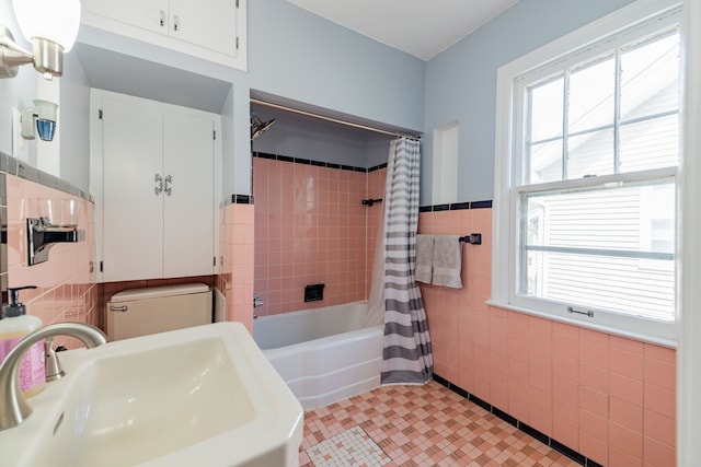 bathroom with a sink, tile patterned floors, shower / bath combination with curtain, and tile walls