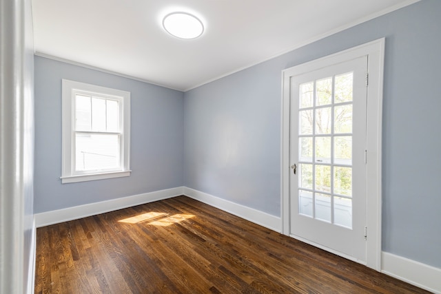 empty room with crown molding, baseboards, and dark wood-type flooring
