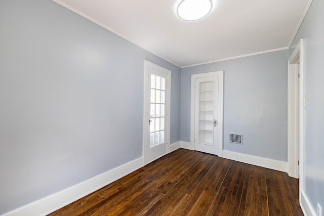 empty room with crown molding, baseboards, dark wood-style floors, and visible vents
