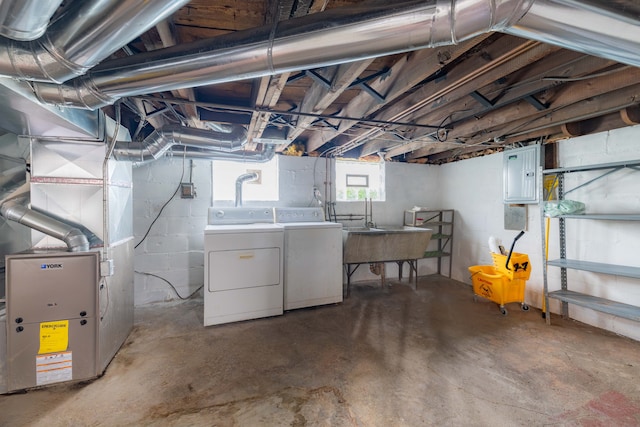 basement with heating unit, electric panel, a sink, and washer and dryer