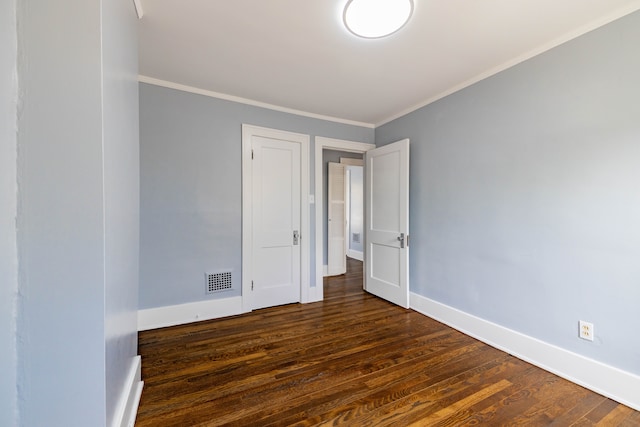 unfurnished room featuring crown molding, baseboards, dark wood-style flooring, and visible vents