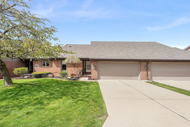 ranch-style house with a garage, a front lawn, brick siding, a shingled roof, and concrete driveway
