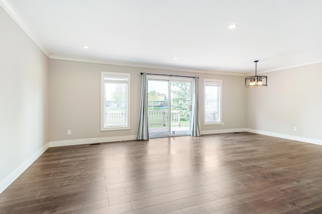 unfurnished room with crown molding, baseboards, an inviting chandelier, and dark wood finished floors