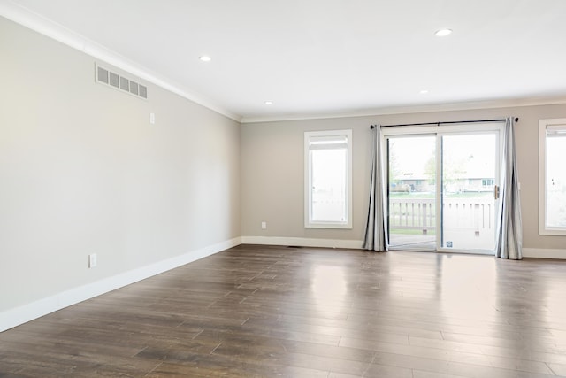 unfurnished room featuring crown molding, baseboards, dark wood-style floors, and visible vents
